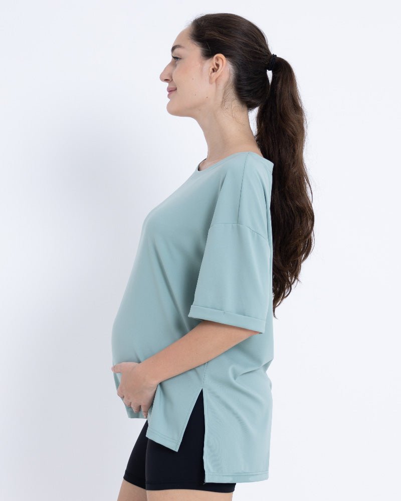 Pregnant woman wearing Breezy-Comfort™ maternity t shirt in light blue with stretchy, breathable fabric and loose fit