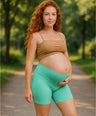Pregnant woman wearing high-waisted aqua maternity shorts with gentle belly support in outdoor setting